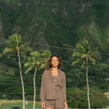 Woman wearing loose button up, smocked tube top and short in medium brown linen.
