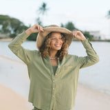 Woman wearing loose button up with smocked tube top and short in medium green linen.