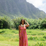 woman wearing a pink tie back maxi dress with lei print