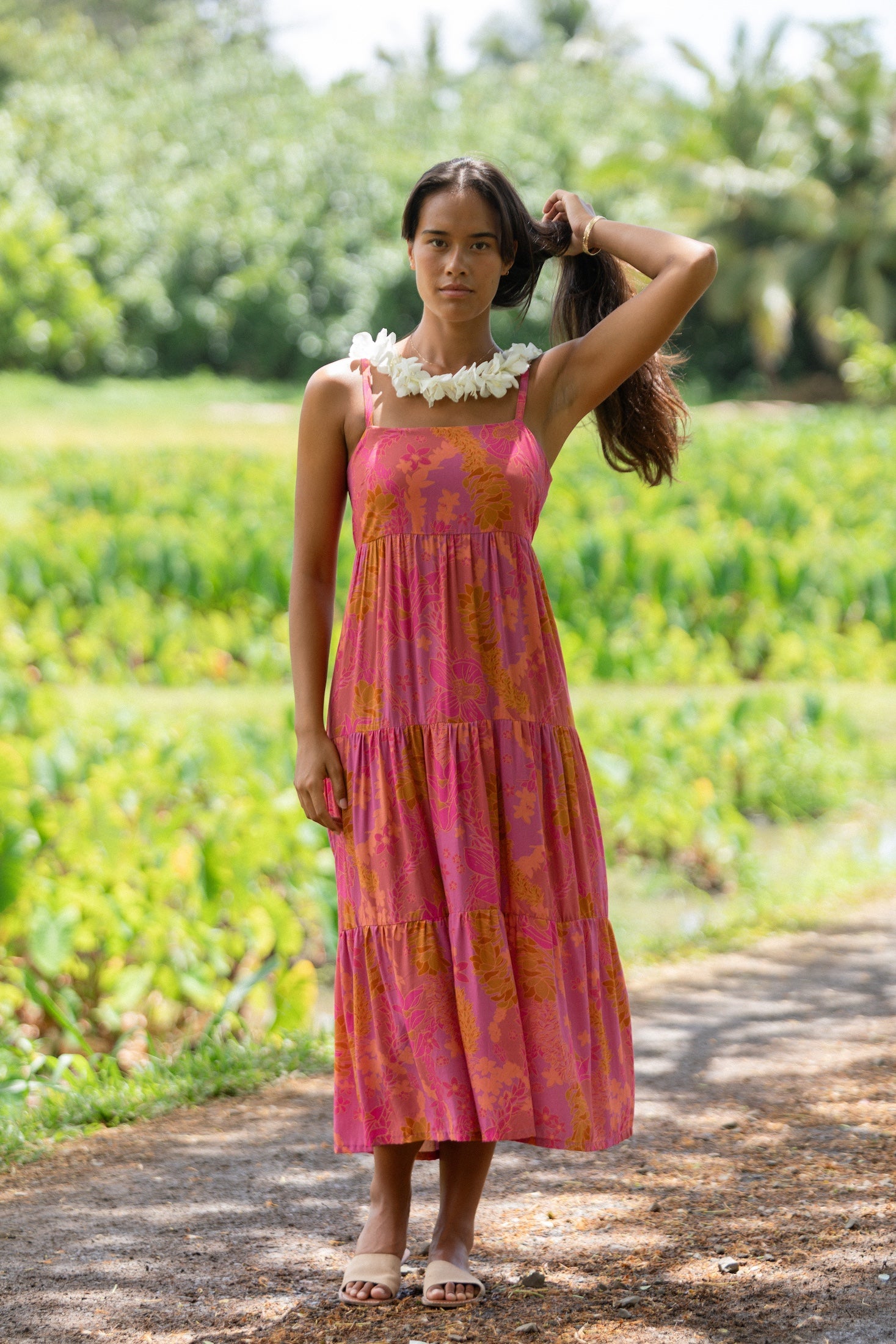 woman wearing a pink tie back maxi dress with lei print