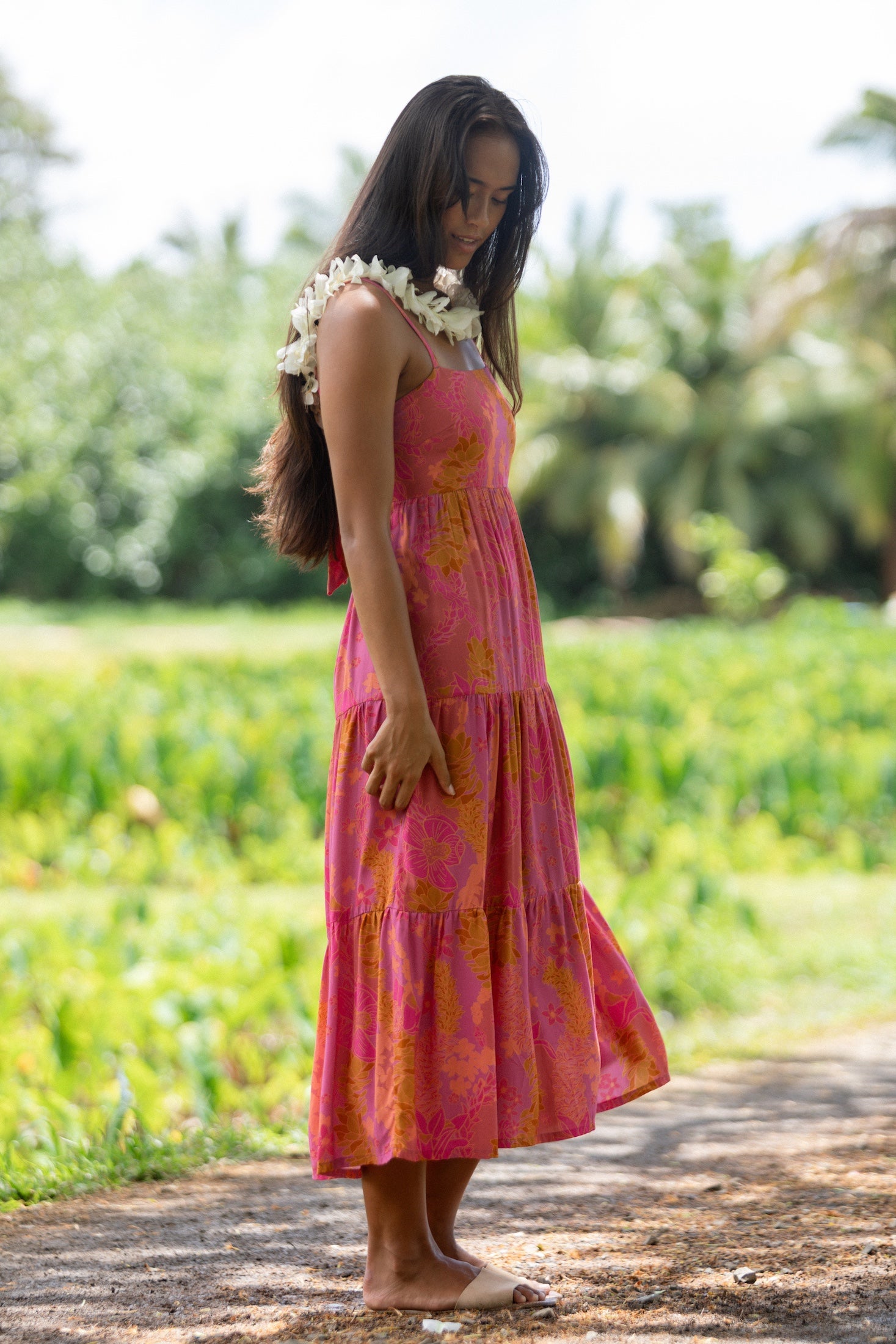 woman wearing a pink tie back maxi dress with lei print