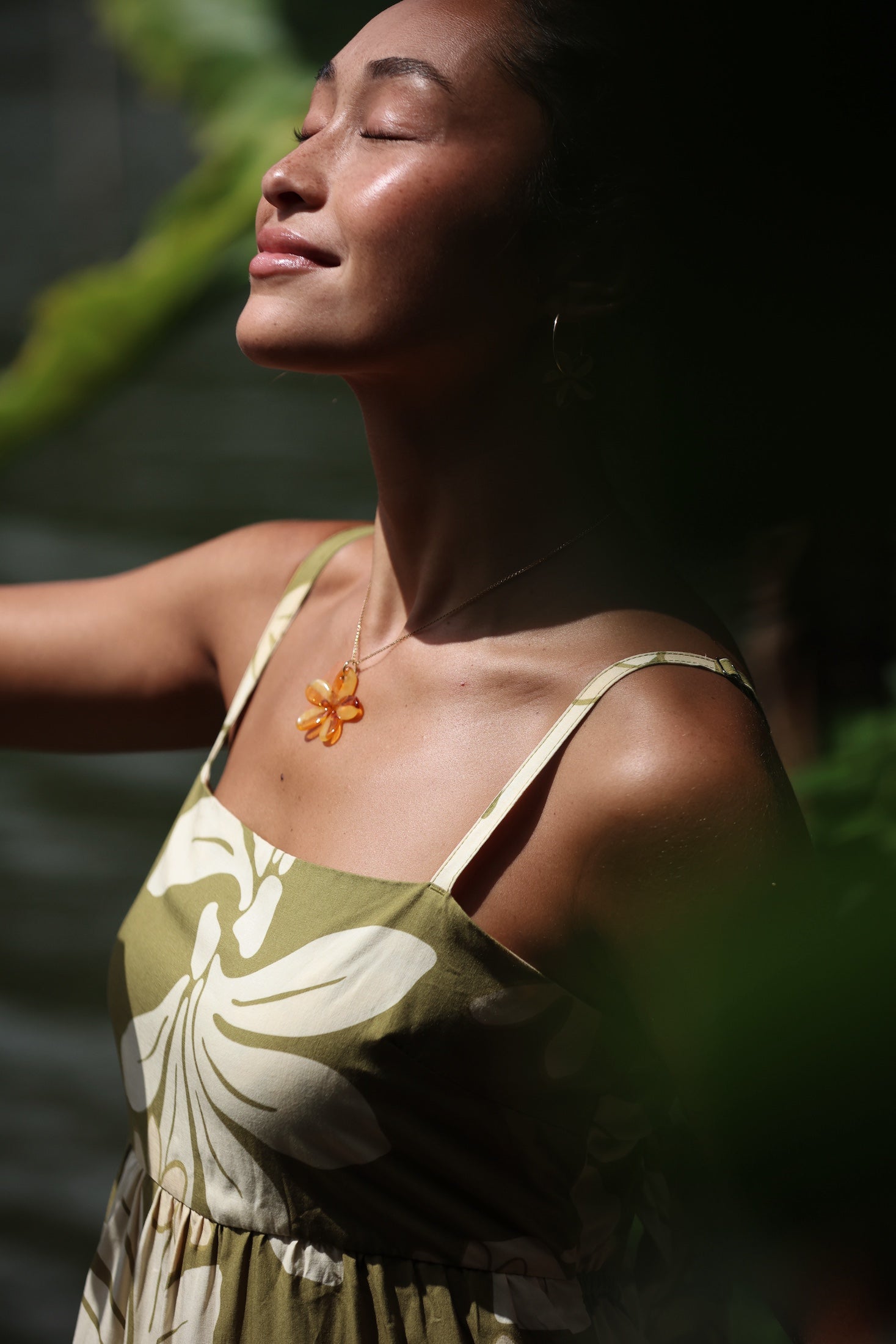 woman with brown hair wearing yellow glass plumeria necklace and earrings