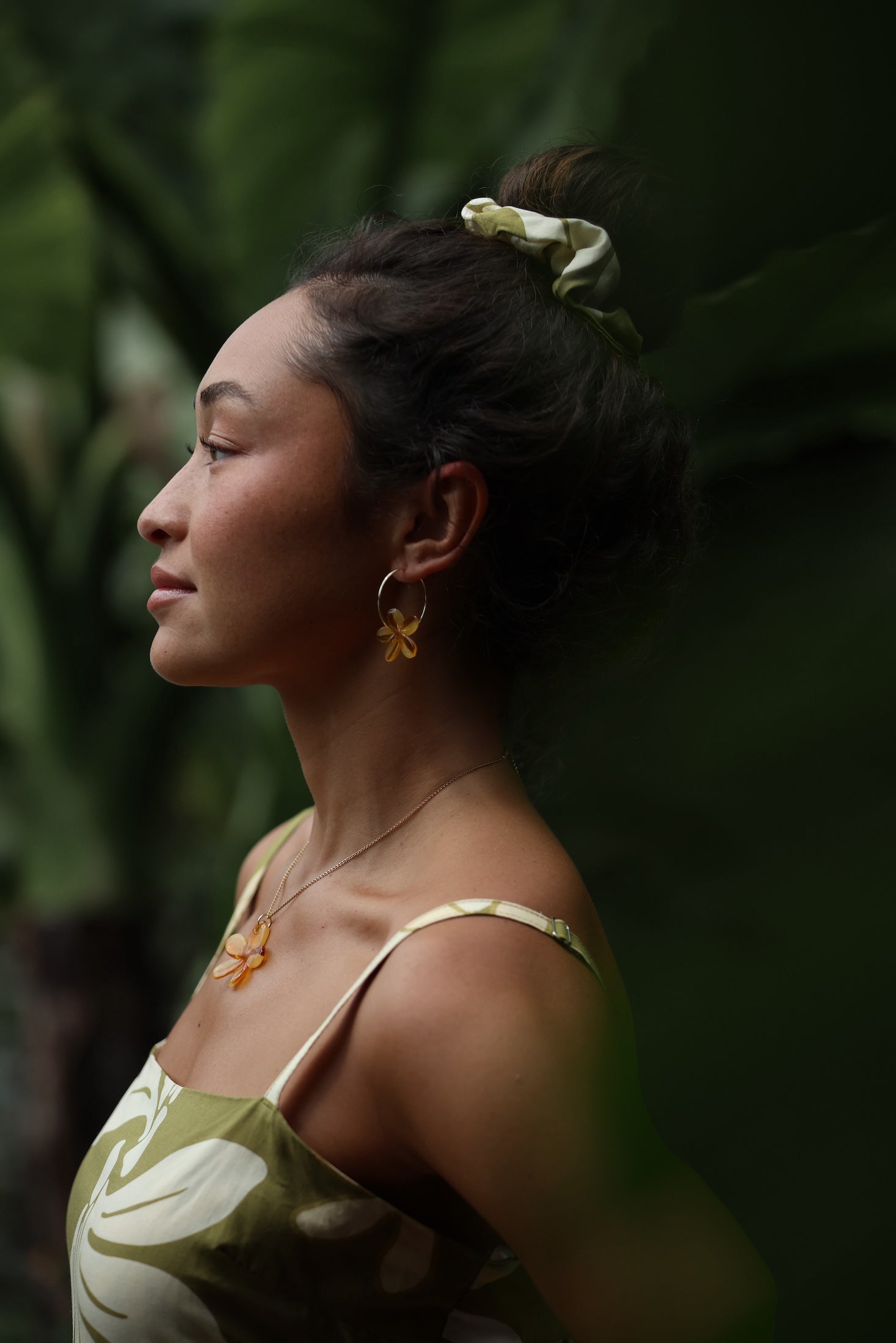 woman with brown hair wearing yellow glass plumeria necklace and earrings