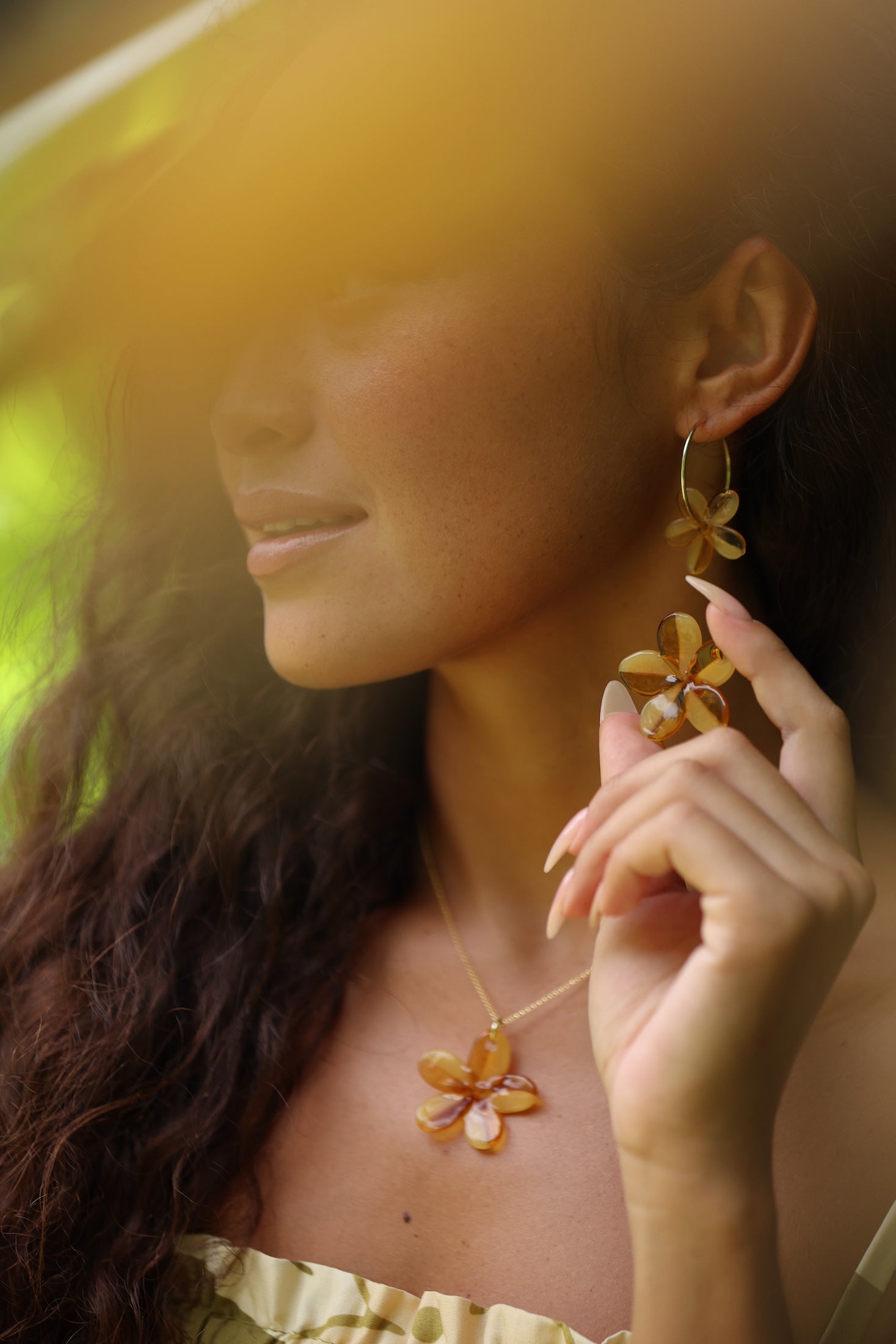 woman with brown hair wearing yellow glass plumeria necklace and earrings