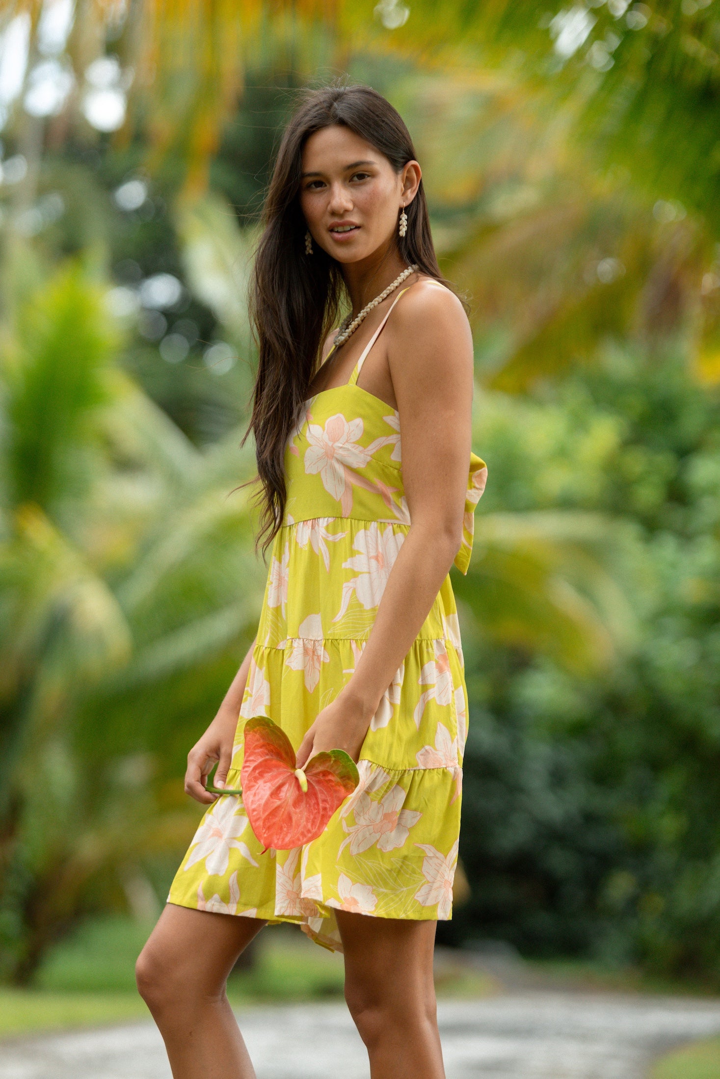 woman wearing a bright green tie back mini dress with orchid print