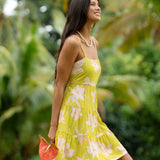 woman wearing a bright green tie back mini dress with orchid print
