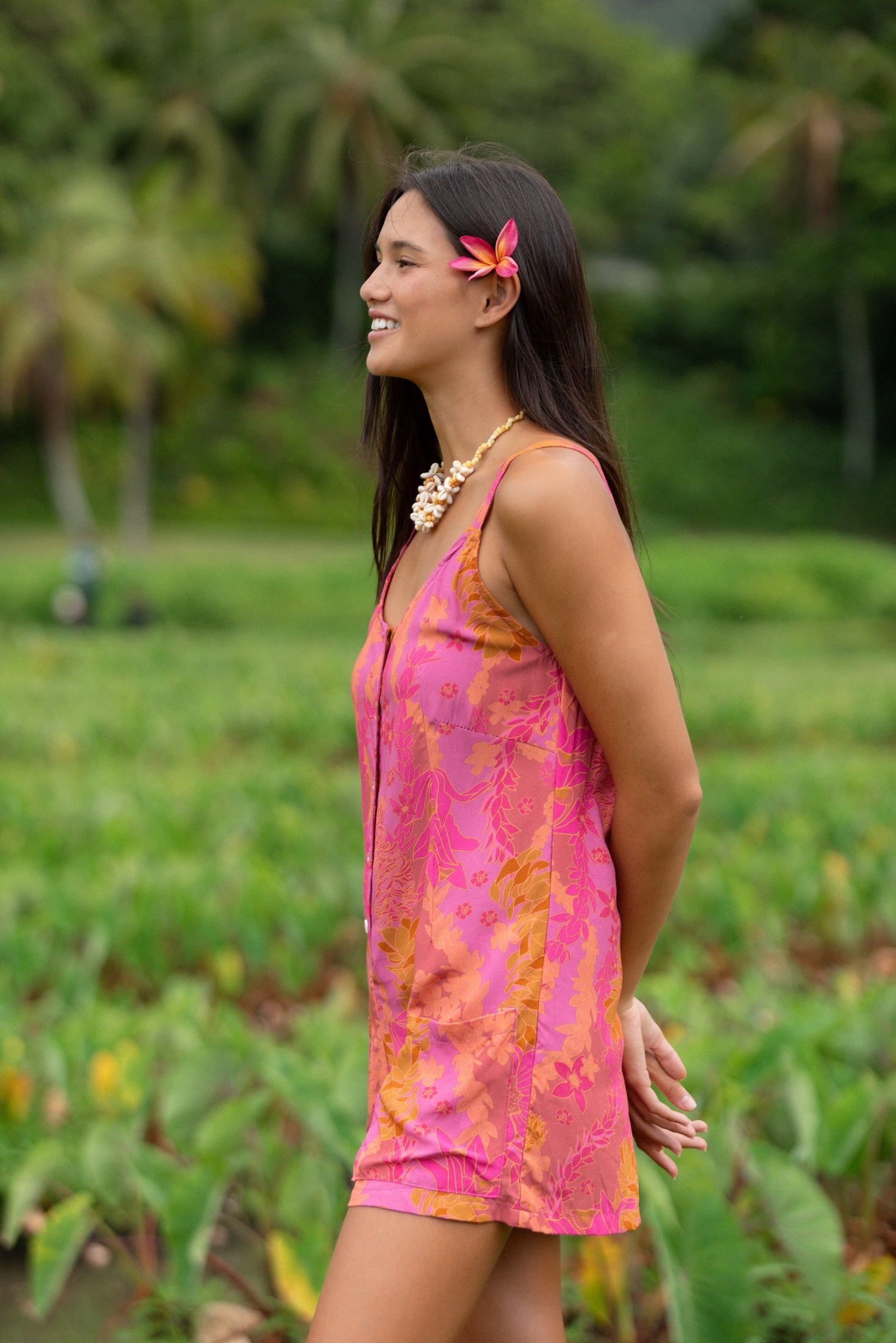 woman wearing a pink tie back romper with lei print