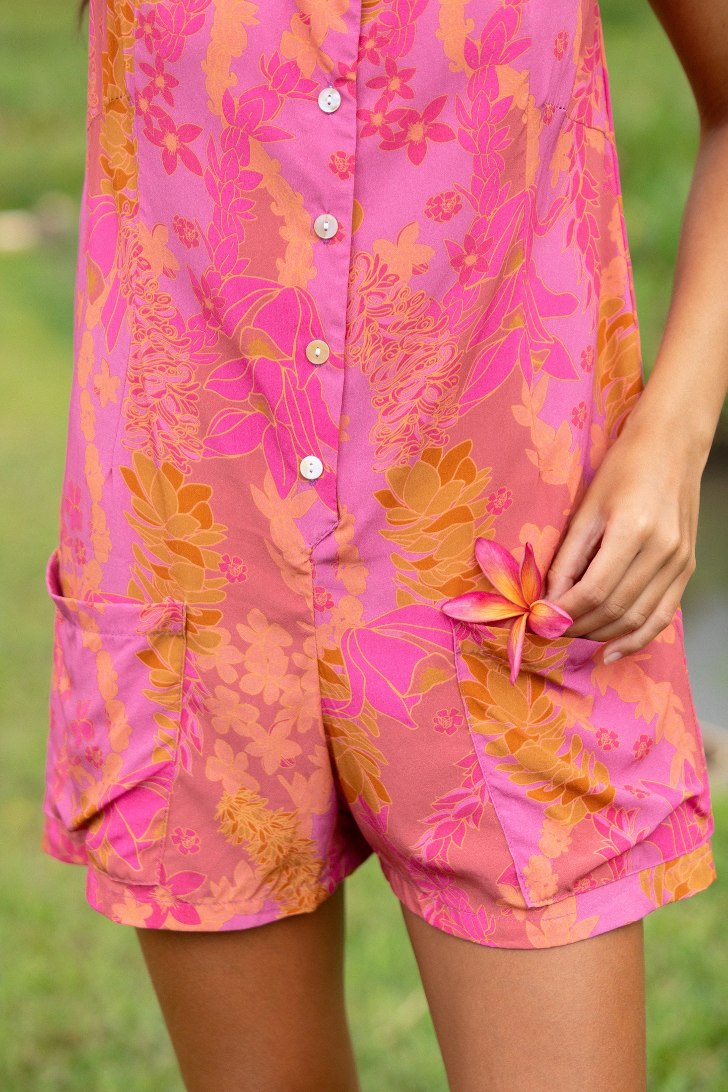 woman wearing a pink tie back romper with lei print
