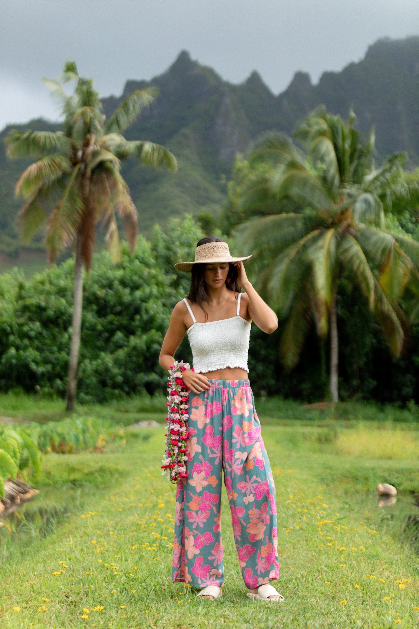 woman with brown hair wearing teal flowy pants with orange and pink foral print