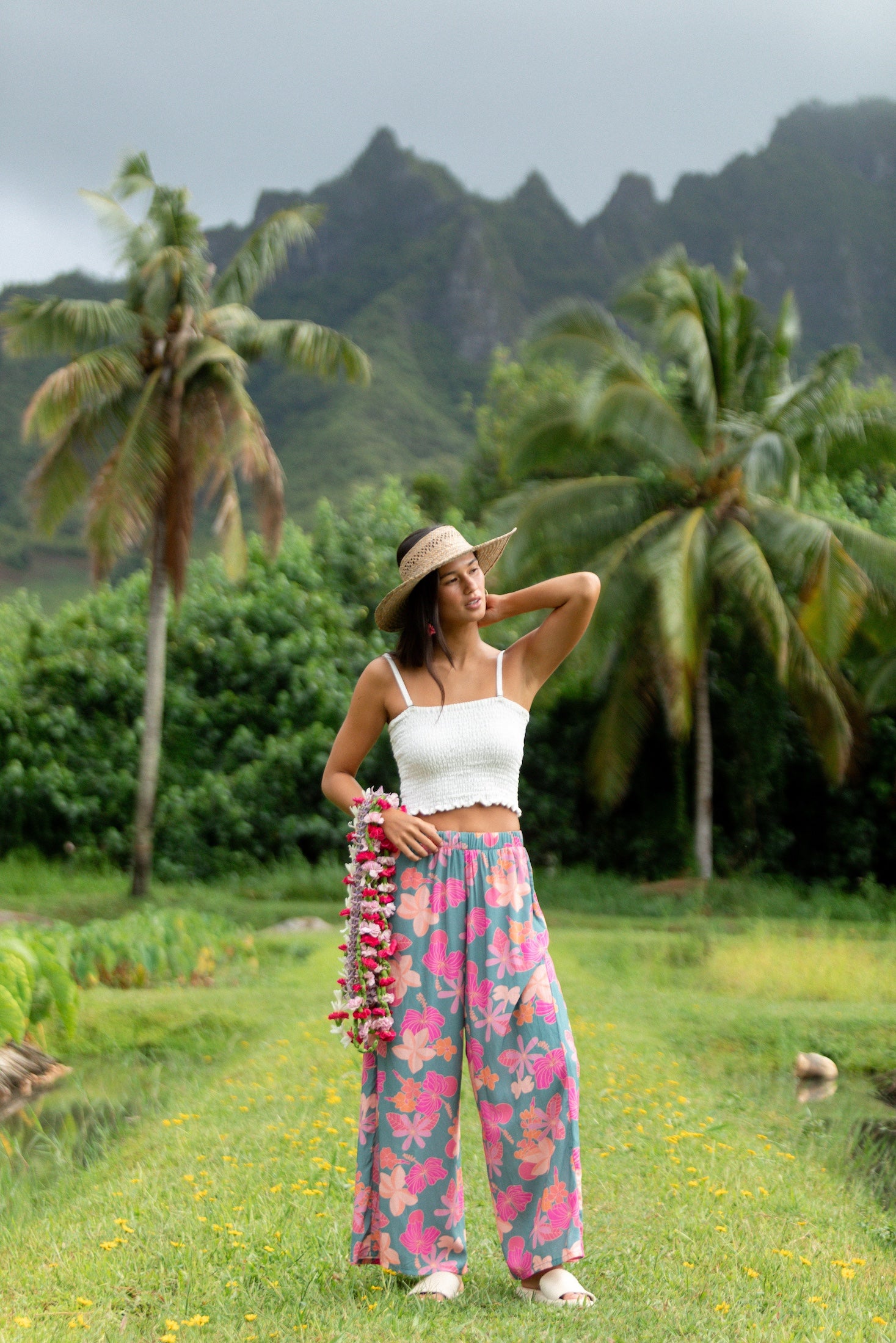 woman with brown hair wearing teal flowy pants with orange and pink foral print