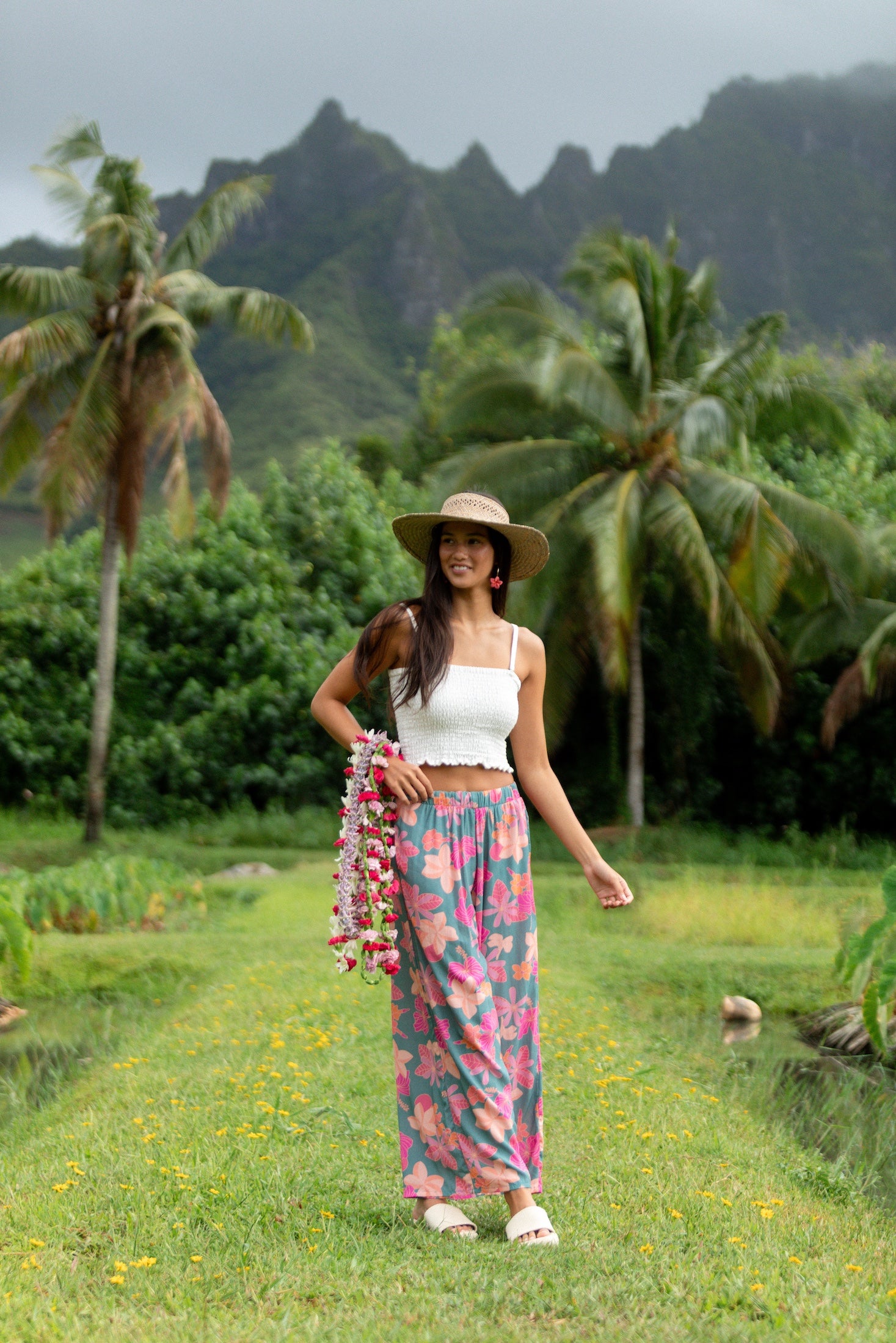 woman with brown hair wearing teal flowy pants with orange and pink foral print
