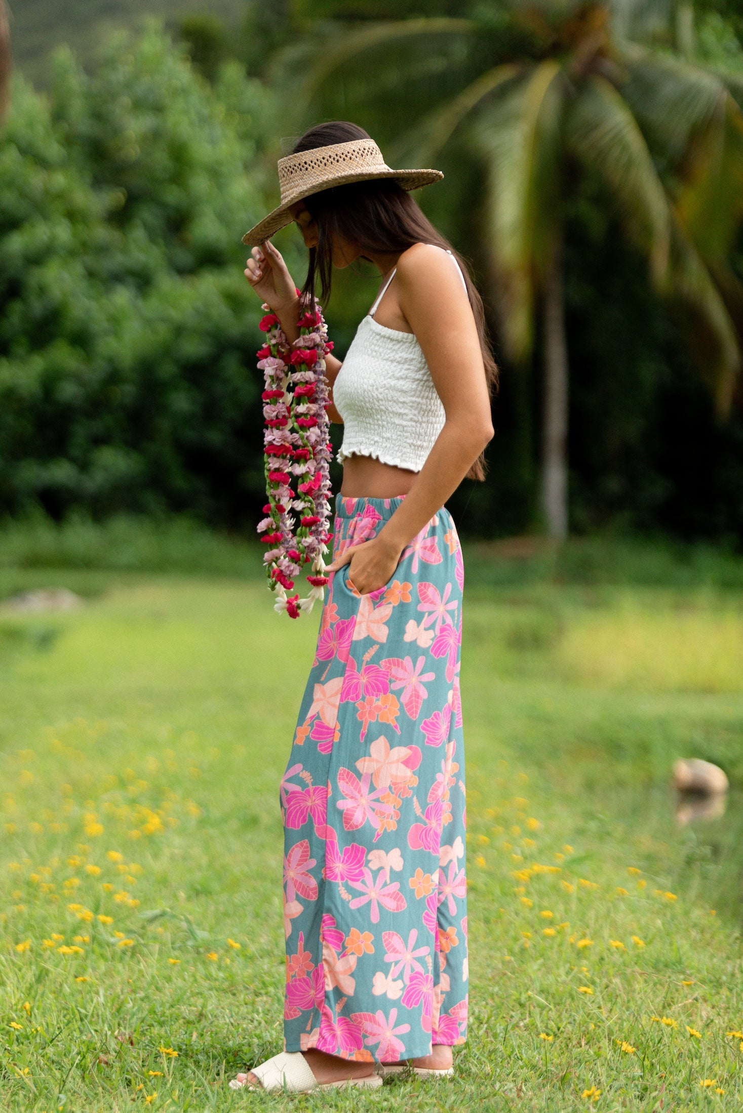 woman with brown hair wearing teal flowy pants with orange and pink foral print