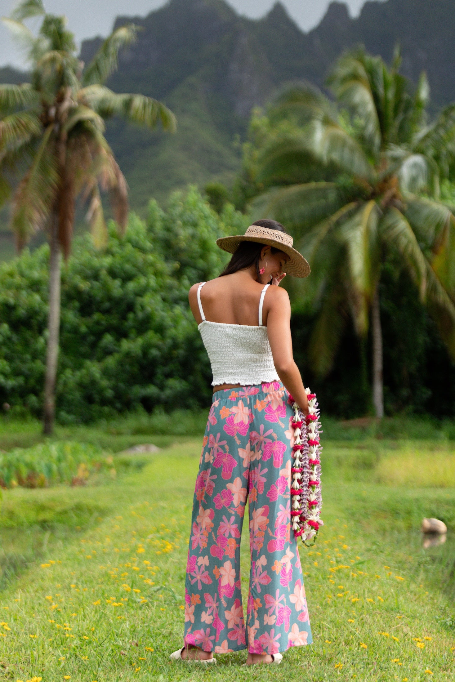 woman with brown hair wearing teal flowy pants with orange and pink foral print