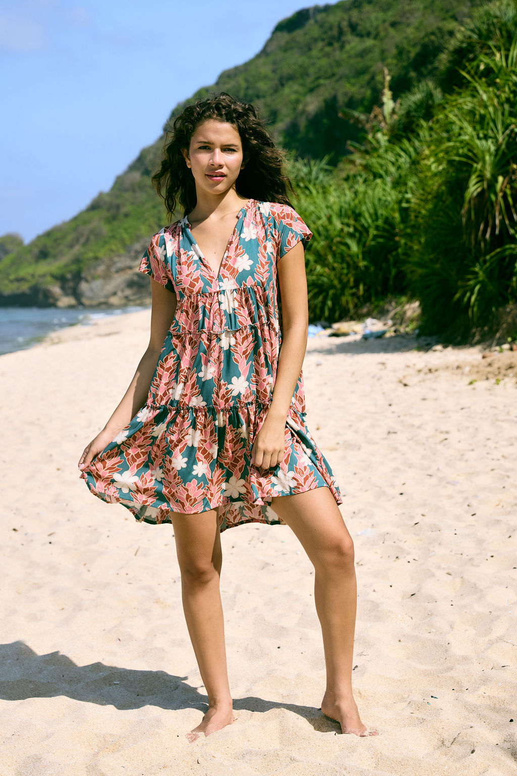 woman with brown hair wearing a deep v cut flowy dress with red ginger and tiare print