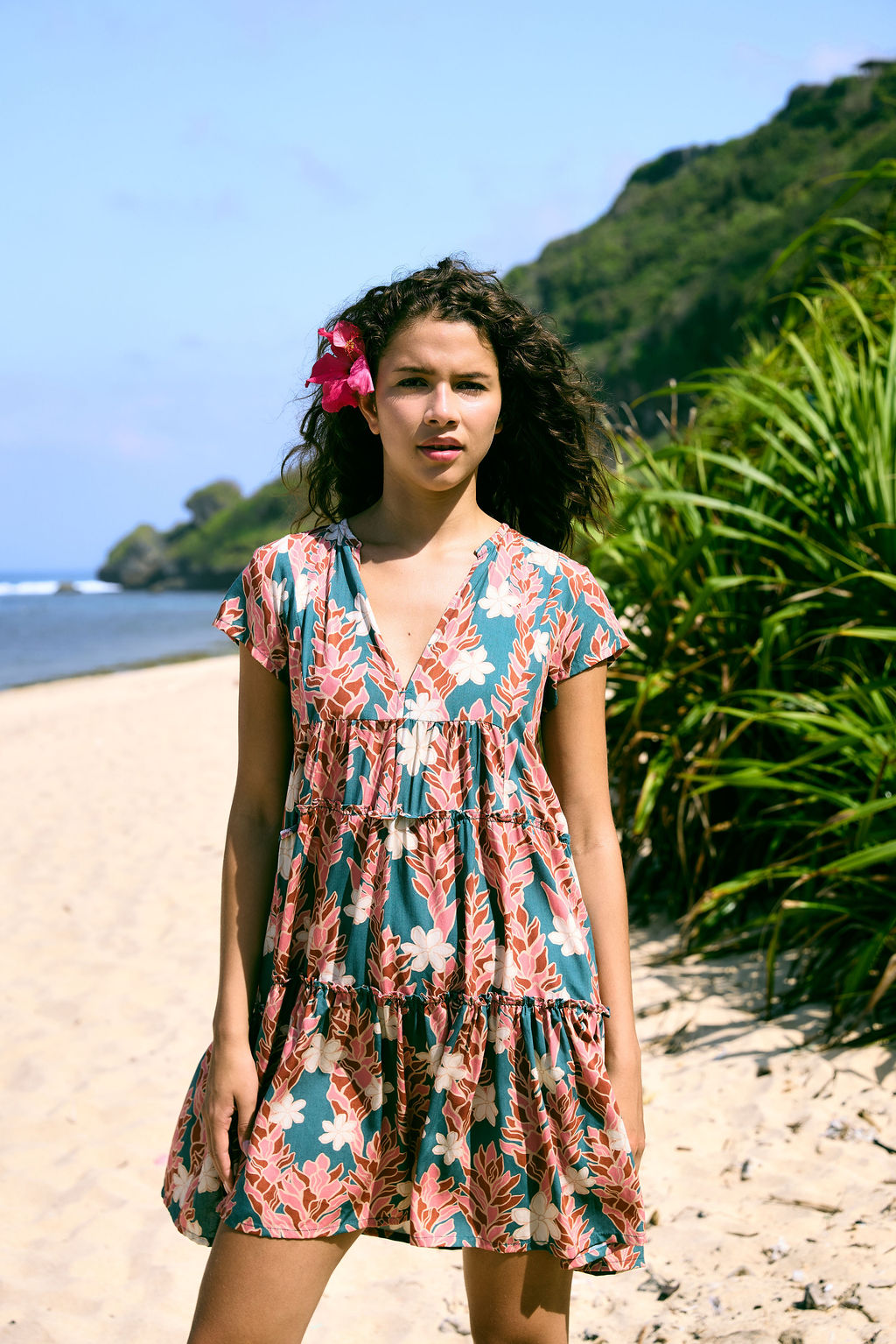woman with brown hair wearing a deep v cut flowy dress with red ginger and tiare print