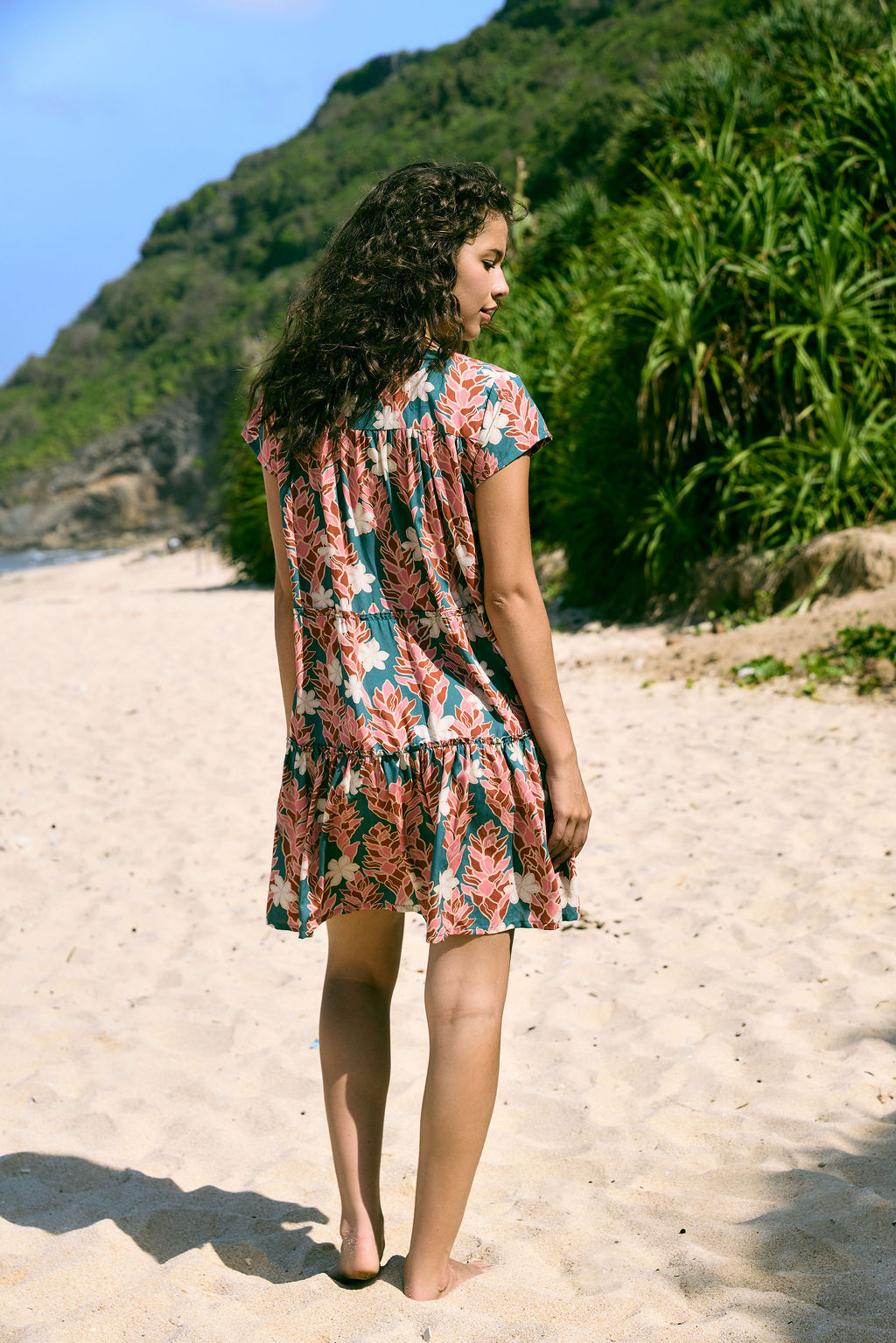 woman with brown hair wearing a deep v cut flowy dress with red ginger and tiare print