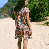 woman with brown hair wearing a deep v cut flowy dress with red ginger and tiare print