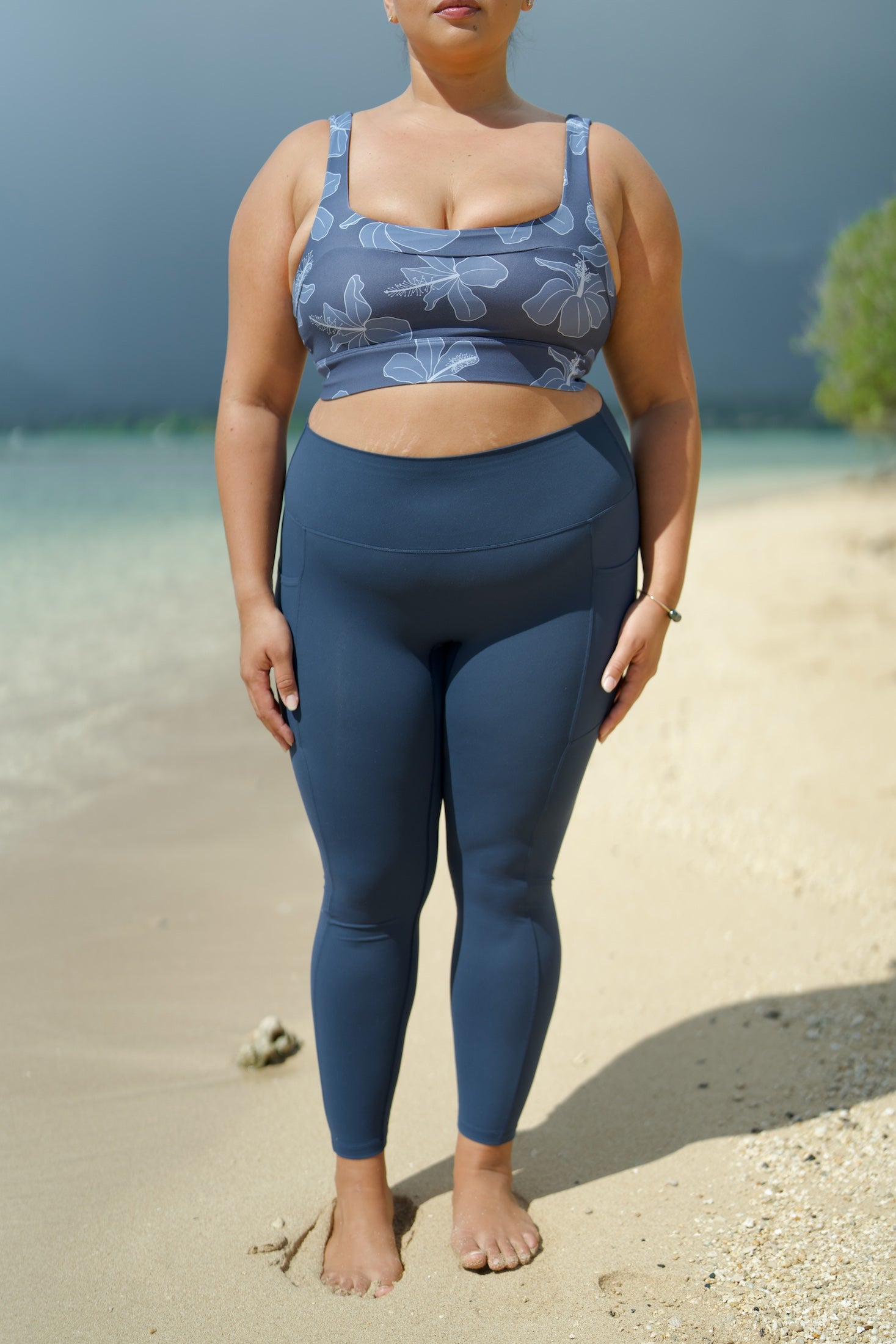 woman wearing a sports bra with blue hibiscus pattern and blue workout legging with pockets