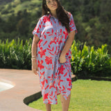 woman with brown hair wearing a maxi button up dress with periwinkle background and bright red hibiscus print.