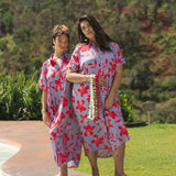 woman with brown hair wearing a maxi button up dress with periwinkle background and bright red hibiscus print.