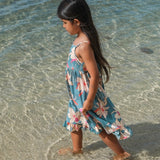 little girl wearing a teal flowy dress with cream colored orchid pattern
