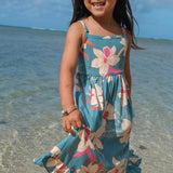 little girl wearing a teal flowy dress with cream colored orchid pattern