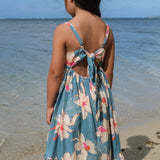 little girl wearing a teal flowy dress with cream colored orchid pattern