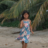 little girl wearing a teal flowy dress with cream colored orchid pattern