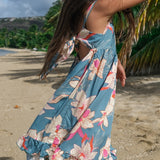 little girl wearing a teal flowy dress with cream colored orchid pattern