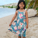 little girl wearing a teal flowy dress with cream colored orchid pattern