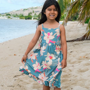 little girl wearing a teal flowy dress with cream colored orchid pattern