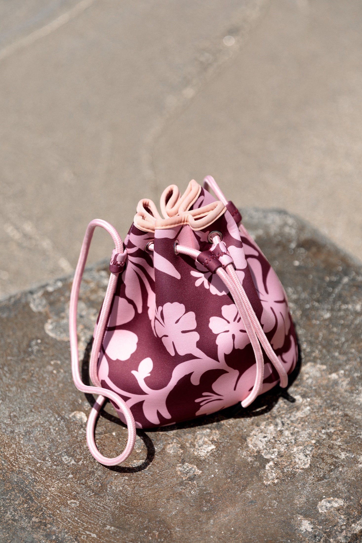 brown neoprene drawstring crossbody purse with pink hibiscus pattern