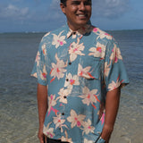 man wearing a teal aloha button up shirt with cream colored orchid pattern