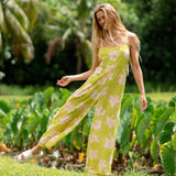 woman wearing a bright green tie back jumpsuit with orchid print