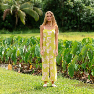woman wearing a bright green tie back jumpsuit with orchid print