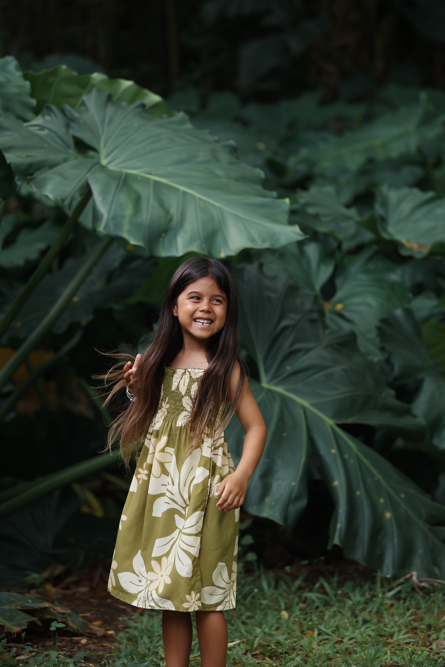 little girl wearing spaghetti strap dress in green print with naupaka pattern
