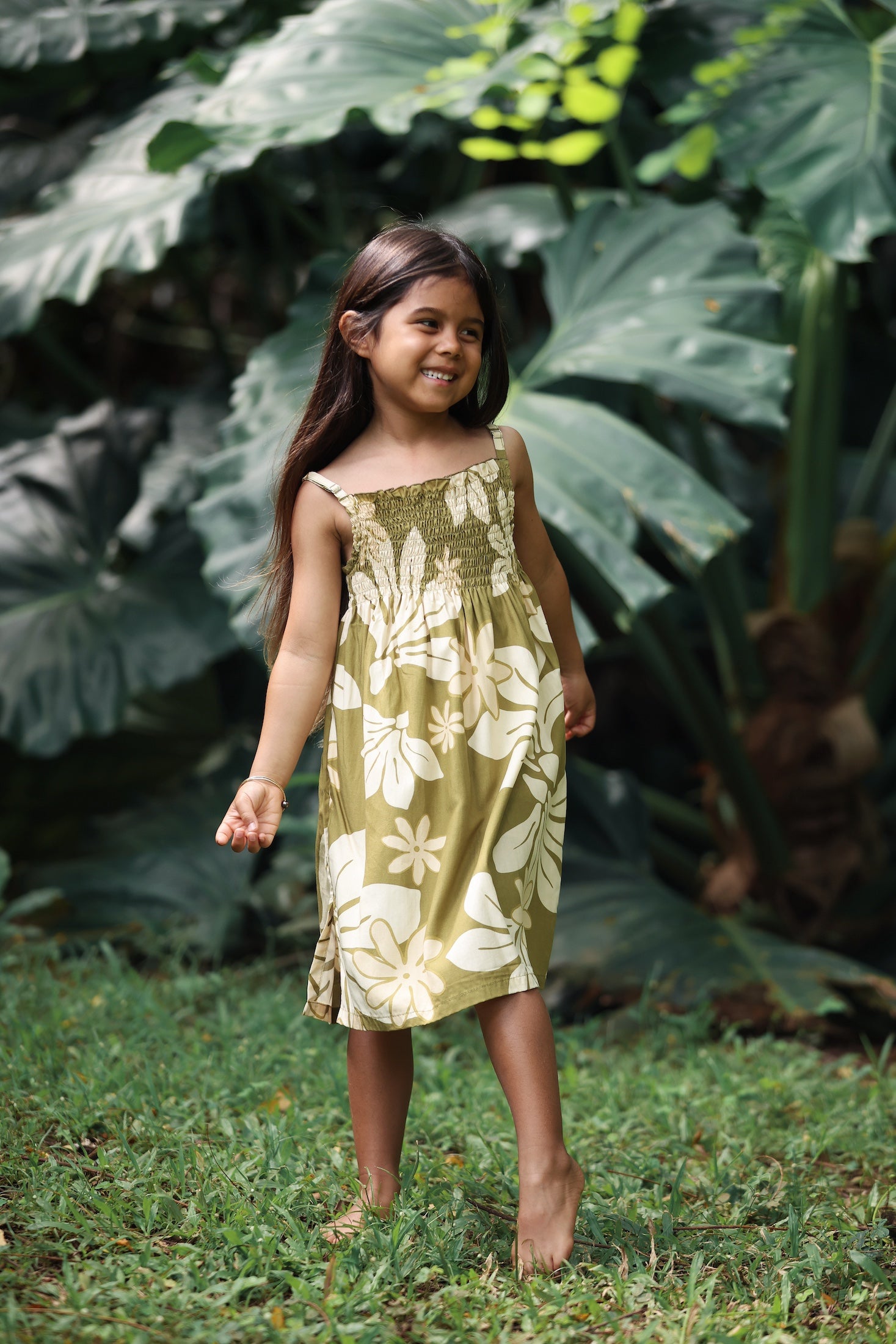 little girl wearing spaghetti strap dress in green print with naupaka pattern