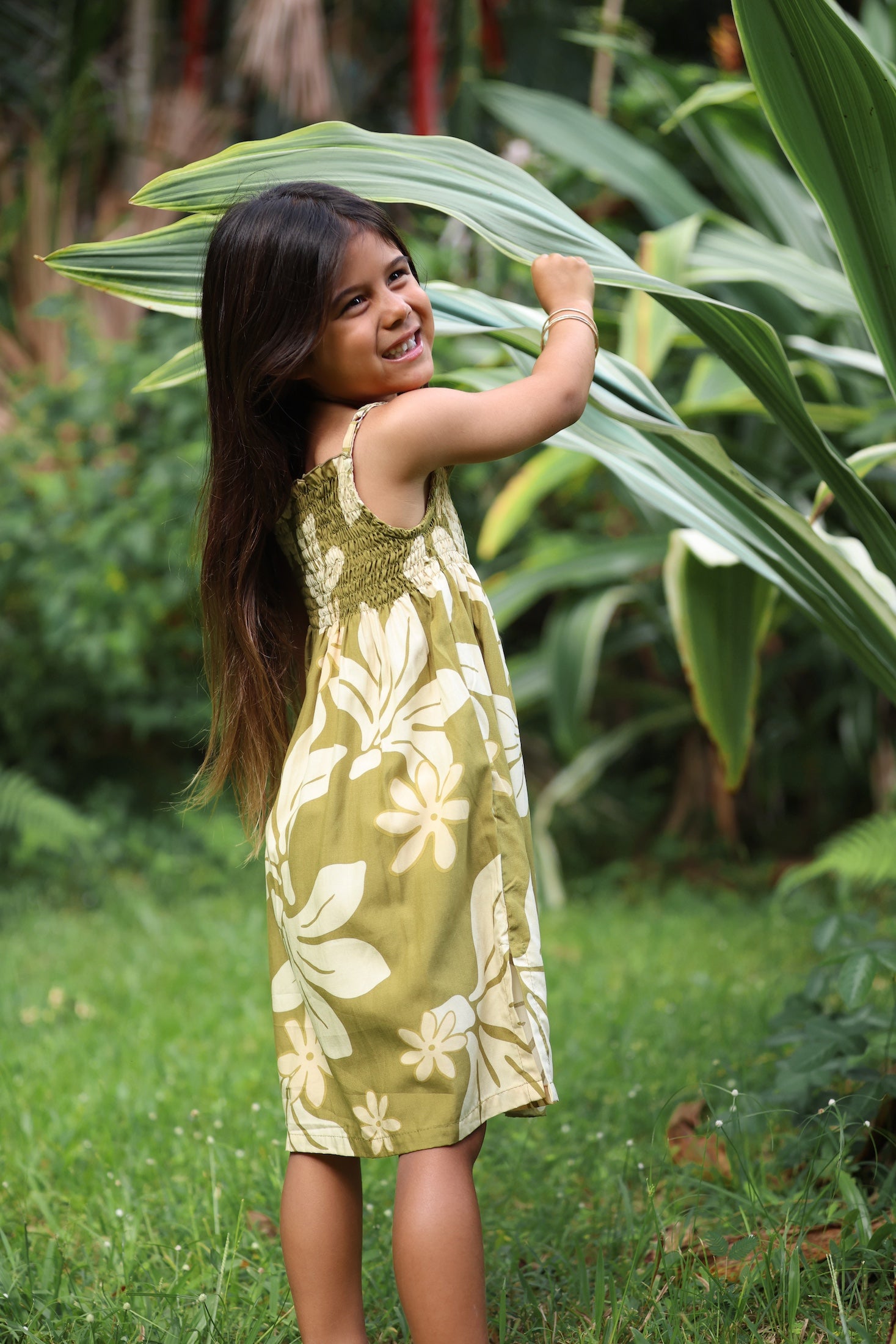 little girl wearing spaghetti strap dress in green print with naupaka pattern