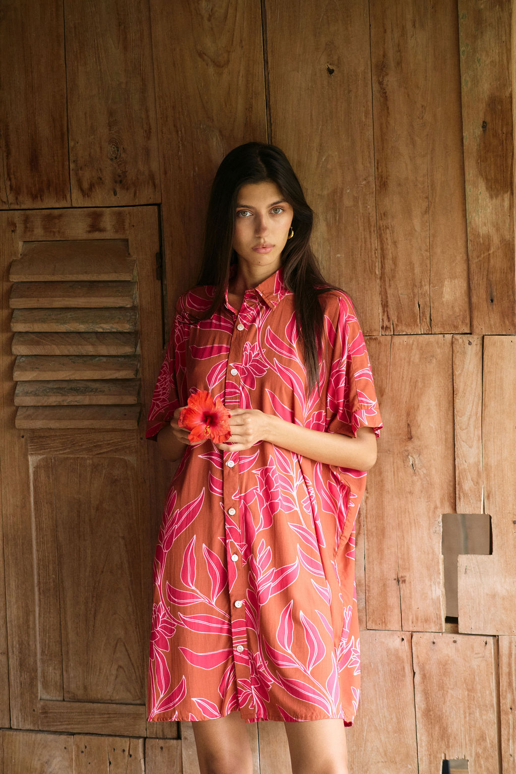 A woman with dark hair wears a YIREH collared, button-up dress. It is the Kaimana Dress in the Garden 'Awapuhi print.