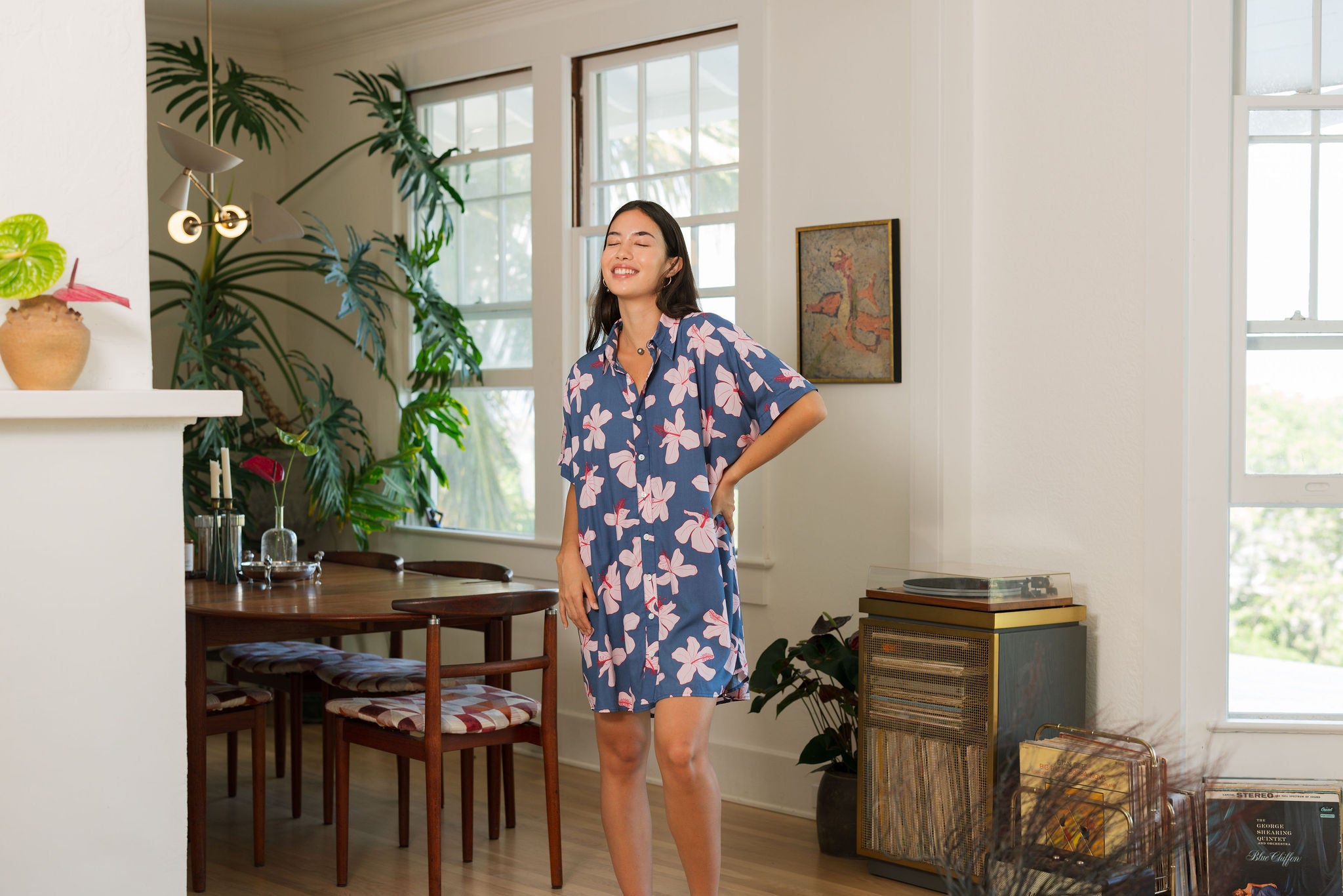 woman with black hair wearing a button up dress in a navy color with pink hibiscus blossoms