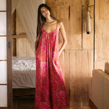 A woman with dark hair wears a YIREH v-neck, wide legged jumpsuit. It is the Laney Jumpsuit in the Garden 'Awapuhi print.