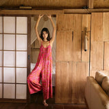 A woman with dark hair wears a YIREH v-neck, wide legged jumpsuit. It is the Laney Jumpsuit in the Garden 'Awapuhi print.