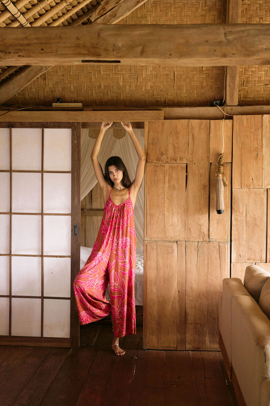 A woman with dark hair wears a YIREH v-neck, wide legged jumpsuit. It is the Laney Jumpsuit in the Garden 'Awapuhi print.