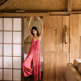 A woman with dark hair wears a YIREH v-neck, wide legged jumpsuit. It is the Laney Jumpsuit in the Garden 'Awapuhi print.
