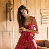 A woman with dark hair wears a YIREH v-neck, wide legged jumpsuit. It is the Laney Jumpsuit in the Garden 'Awapuhi print.