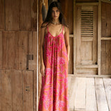 A woman with dark hair wears a YIREH v-neck, wide legged jumpsuit. It is the Laney Jumpsuit in the Garden 'Awapuhi print.
