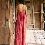 A woman with dark hair wears a YIREH v-neck, wide legged jumpsuit. It is the Laney Jumpsuit in the Garden 'Awapuhi print.