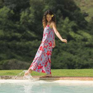 woman with brown hair wearing a jumpsuit with periwinkle background and bright red hibiscus print.