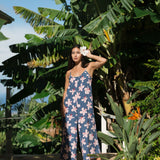 woman with black hair wearing a jumpsuit in a navy color with pink hibiscus blossoms
