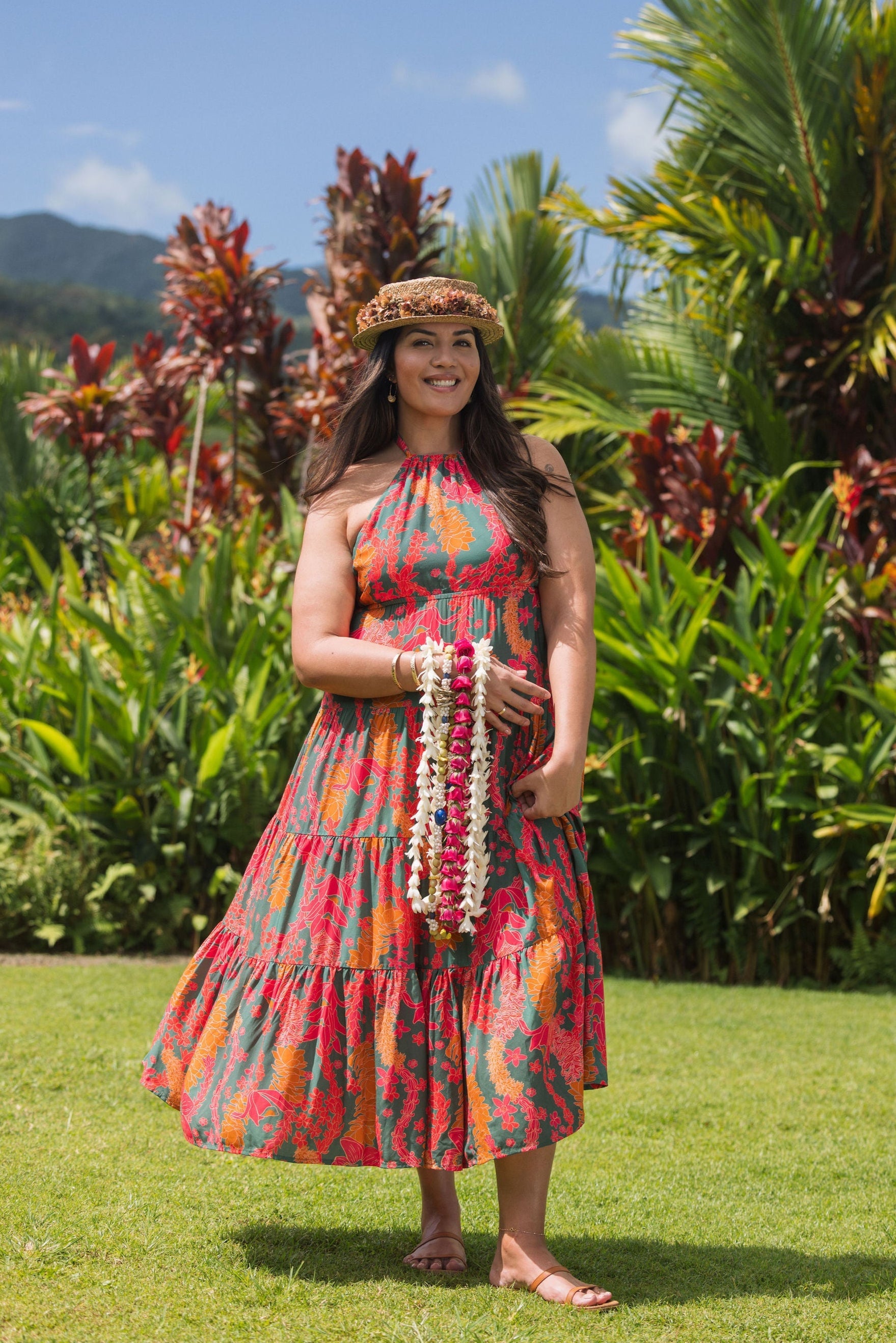 woman with brown hair wearing a colorful flowy maxi dress with tropical lei print